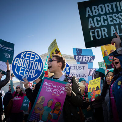 Abortion activists hold signs at rally that read" Keep Abortion Legal" and "Abortion Access for All."