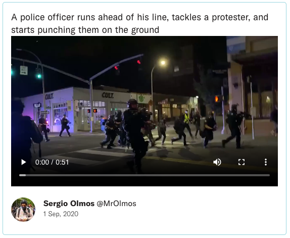 A police officer runs ahead of his line, tackles a protester, and starts punching them on the ground