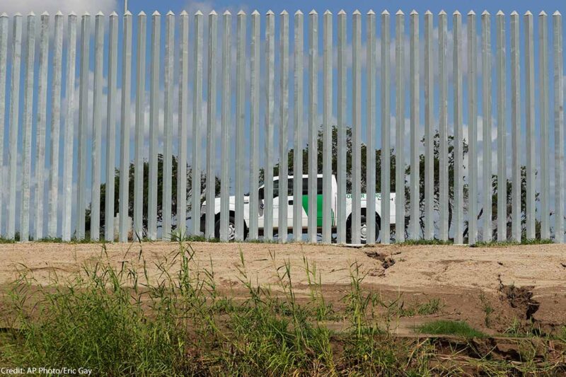 A CBP truck is seen through a border wall