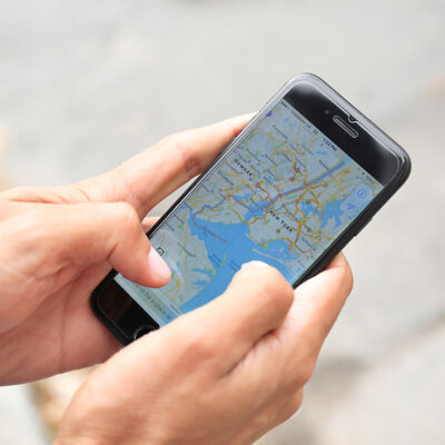 A man holding iPhone with navigation map app open on screen.