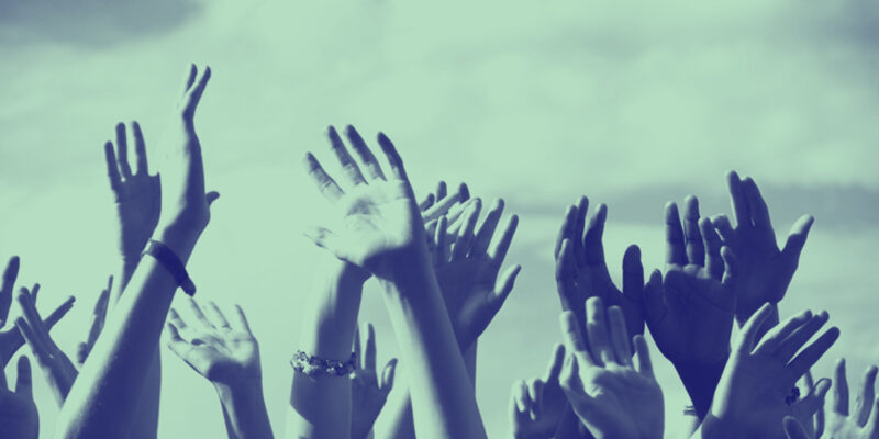 A green tinted image of hands raised in the air.