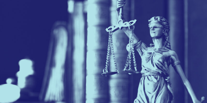 A blue tinted photo of Lady Justice statue holding the scales.
