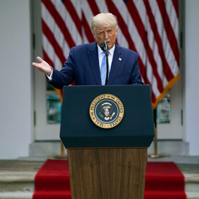President Donald Trump speaks about podium with presidential seal during an event in the Rose Garden of the White House.