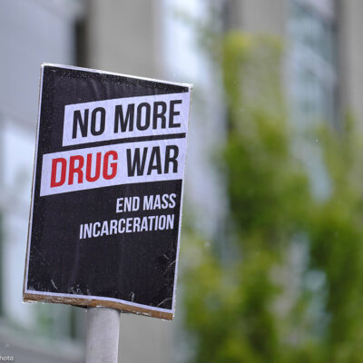Black and white protest sign reads: "No More Drug War, End Mass Incarceration"