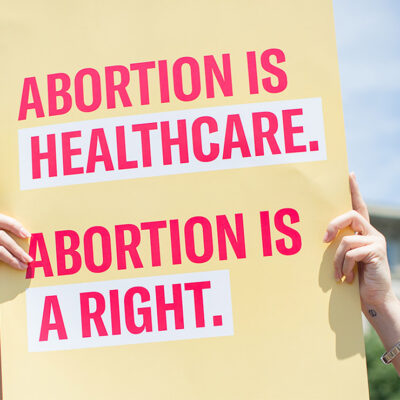 Two hands holding a sign with the text "Abortion is healthcare. Abortion is a right."