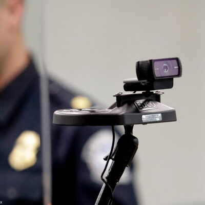 A face recognition camera with a CBP agent in the background.