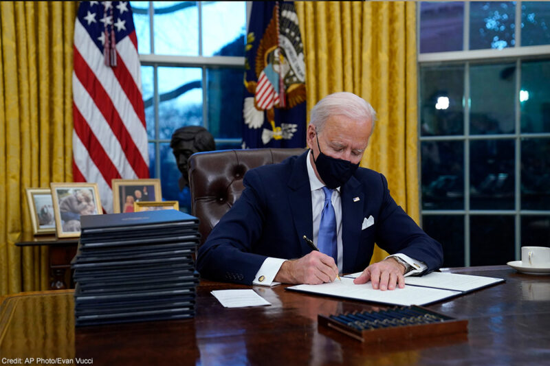 President Joe Biden signs his first executive order in the Oval Office of the White House.