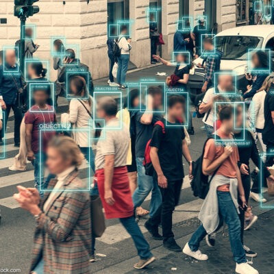 Facial recognition software scanning people walking across a busy intersection.