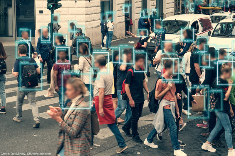 Facial recognition software scanning people walking across a busy intersection.