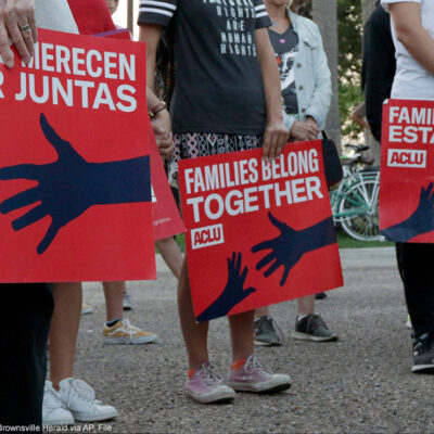 People hold signs that read "families belong together" in both English and Spanish during a vigil.
