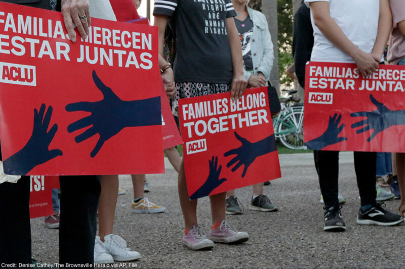 People hold signs that read "families belong together" in both English and Spanish during a vigil.
