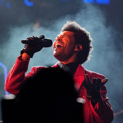 Artist The Weeknd sings into a microphone on stage at Super Bowl 55