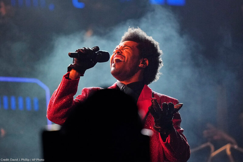 Artist The Weeknd sings into a microphone on stage at Super Bowl 55