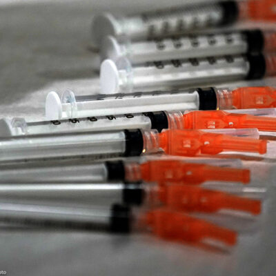 Syringes loaded with the Moderna COVID-19 Vaccine spread on a clinic table