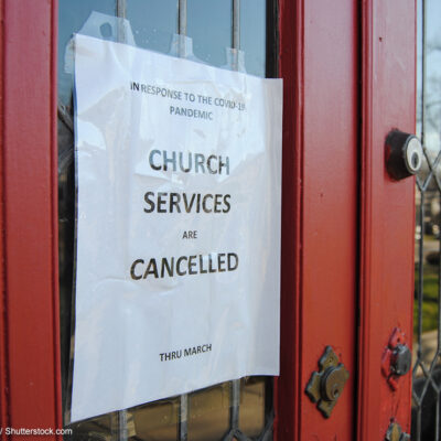 A sign taped to the door of a church announcing services are cancelled due to COVID-19.