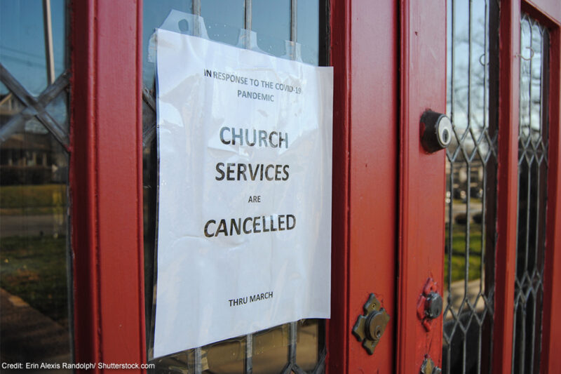 A sign taped to the door of a church announcing services are cancelled due to COVID-19.