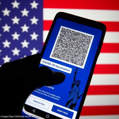 In this photo illustration, Excelsior Pass app which provides digital proof of COVID-19 vaccination or negative test results seen displayed on a smartphone screen in front of the US flag.