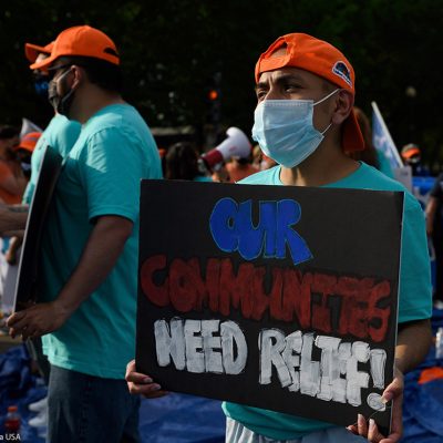 An activist holds sign that reads "Our Communities Need Relief" for immigration reform at a sit-in protest in downtown Washington, D.C.