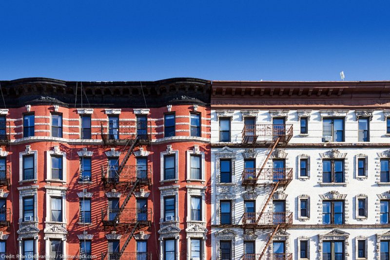 New York City block of old historic apartment buildings in the East Village of Manhattan, with clear blue sky background.