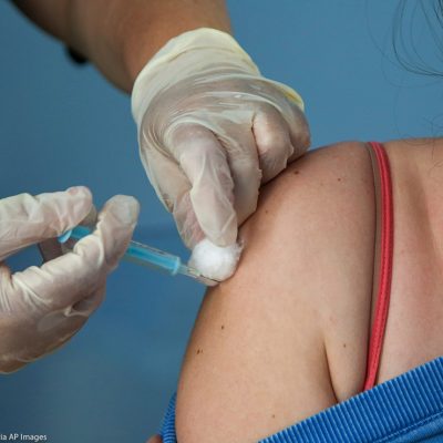 A Covid-19 vaccinator administers the Oxford/AstraZeneca vaccine to a woman at a vaccination centre in London