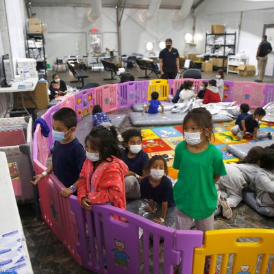 young unaccompanied migrants, from ages 3 to 9, watch television inside a playpen at the U.S. Customs and Border Protection facility