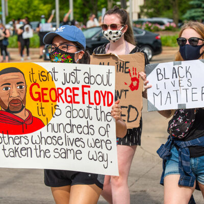 BLM protester holding a sign that says, "It isn't just about George Floyd it is about the hundreds of others whose lives were taken the same way."