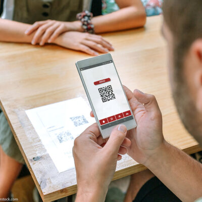 A man uses his phone to scan restaurant QR code on table