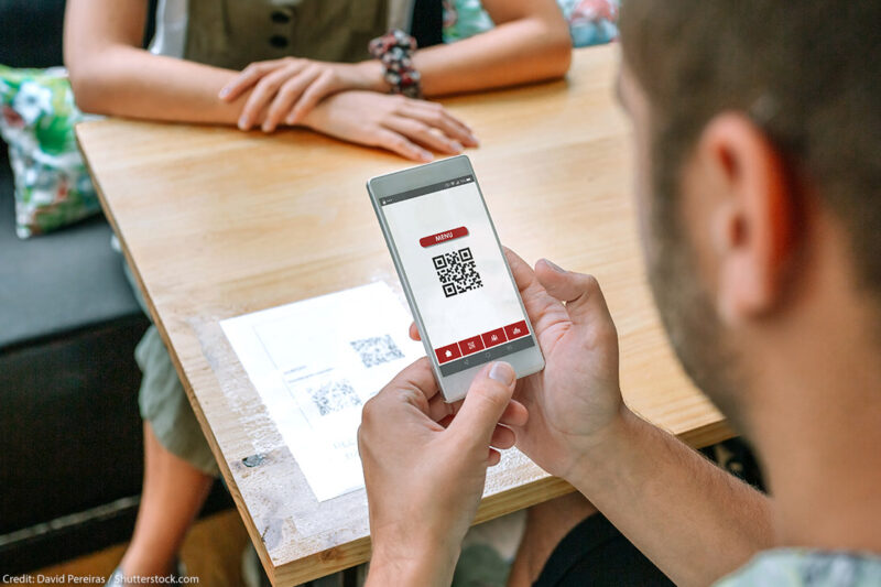 A man uses his phone to scan restaurant QR code on table