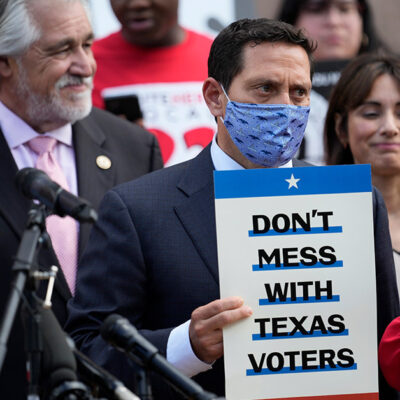 Rep. Trey Martinez Fischer, D-San Antonio, holds a sign that says, "Don't mess with Texas," as he and other Democratic caucus members join a rally on the steps of the Texas Capitol to support voting rights