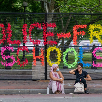 A sign made out of confetti that reads "Police Free Schools" on a gate during a Black Lives Matter protest.