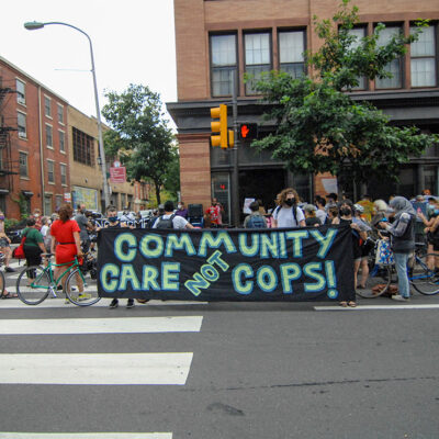Protesters hold a banner calling for investment in communities, not the police