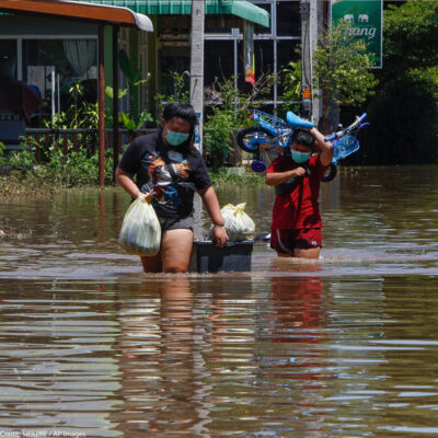 Residents carrying their belongings wade through floodwaters as Pasak Jolasid Dam overflows.