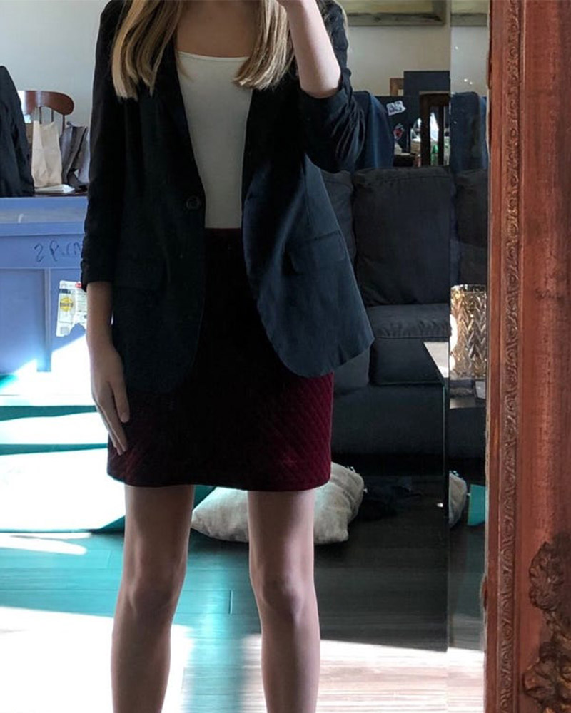 Photo taken in a mirror of a white girl with black shoes, a dark red skirt and a navy blazer over a white shirt.