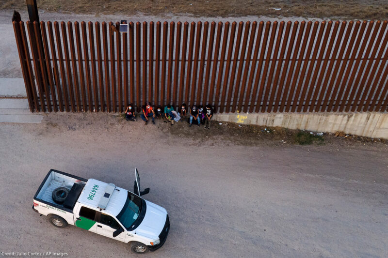 A U.S. Customs and Border Protection vehicle is seen next to migrants after they were detained and taken into custody.
