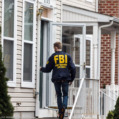 A member of the FBI enters a residence.