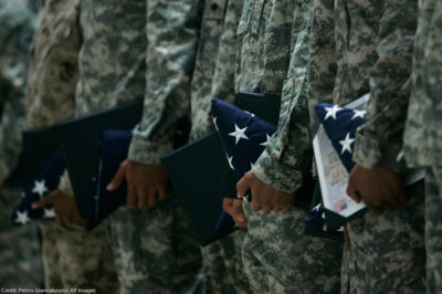 U.S. Army soldiers holding certificates and folded U.S. flags during a ceremony.