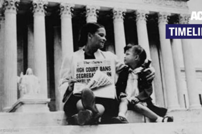 A dated photo of a woman holding a newspaper with a young girl next to her. The newspaper's headline alludes to the "High Court" banning segregation.