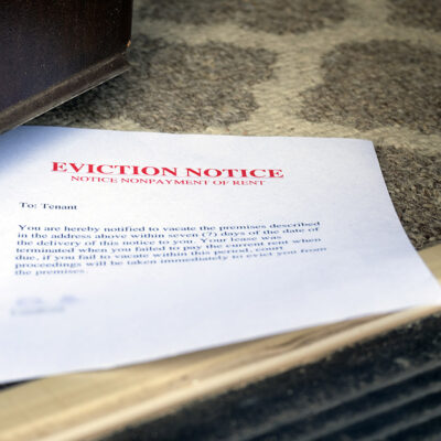 A stock photo of an eviction noticed, placed in an open door.