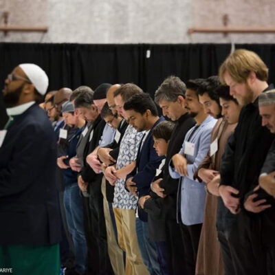 Imam Kariye standing in front of the row of people in prayer.