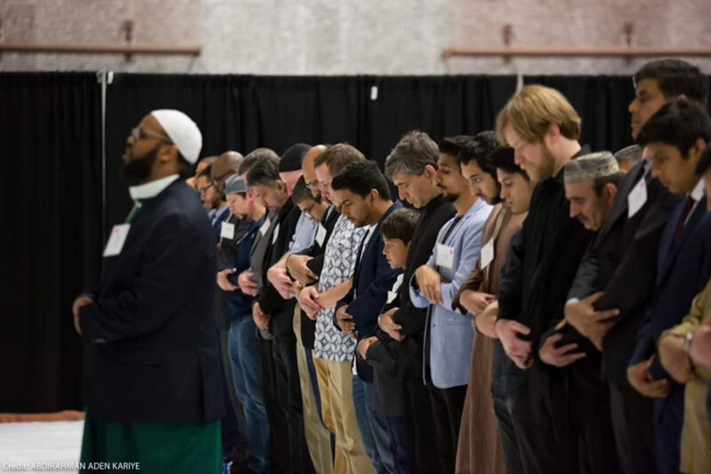 Imam Kariye standing in front of the row of people in prayer.