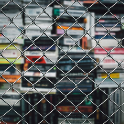 A stack of books behind a chain-link fence.
