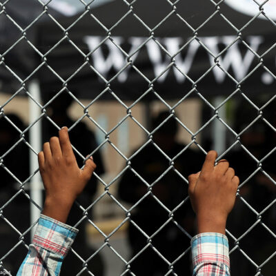 A migrant leans on a fence of the Gateway International Bridge that connects downtown Matamoros, Mexico with Brownsville, Texas.
