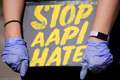 Woman holds a sign stating “Stop AAPI Hate.”