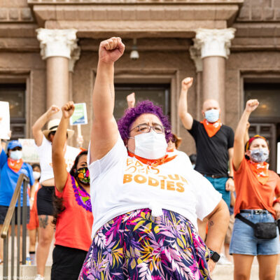 Activists wearing "Bans off our bodies" shirt and throwing fists in the air