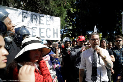 Man speaking to a crowd, rallying for support at a free speech protest.