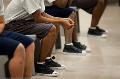 Four children (with faces hidden) sitting inside a detention center.