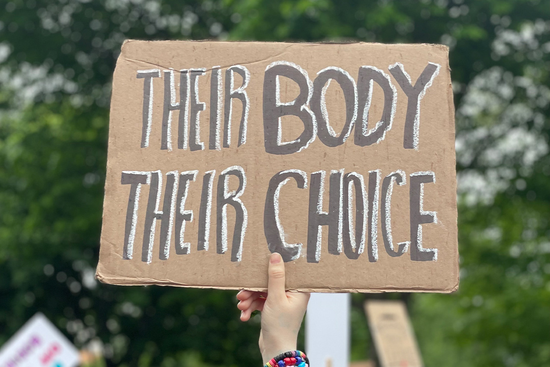 A protestor holding up a sign reading, "THEIR BODY THEIR CHOICE."