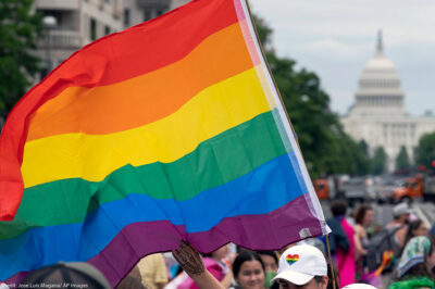 A rainbow flag with the U.S. capitol in the background.