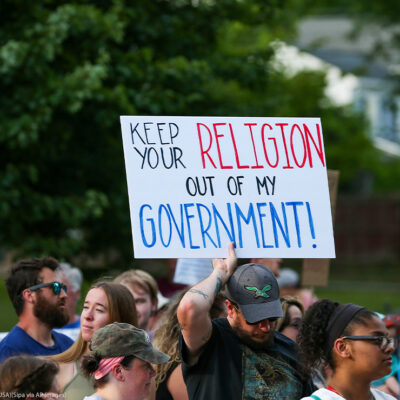 A protestor holds a sign reading "Keep Your Religion Out of My Government" during a rally at Memorial Park in Danville, Pennsylvania.