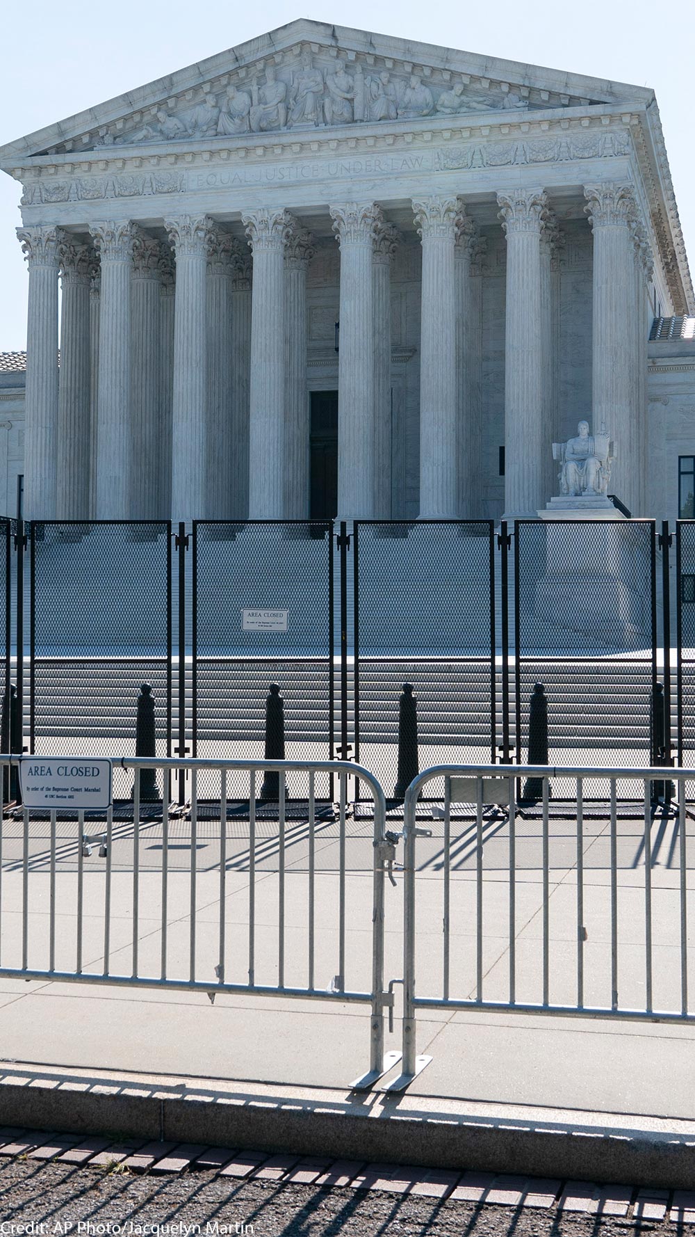 A view front of the U.S. Supreme Court Building behind riot gates.